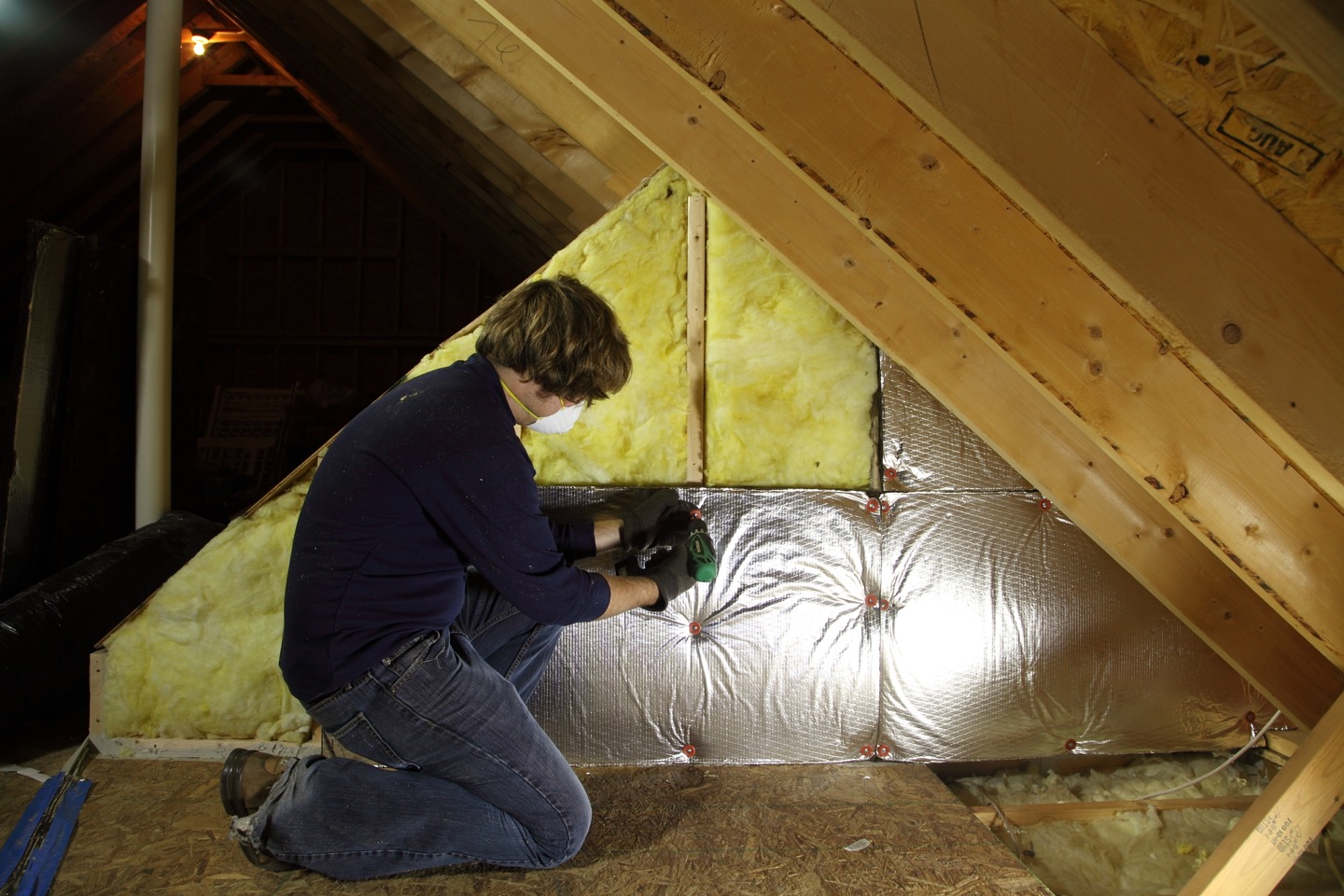 Mineralull og folie under arbeid med loftsisolering.